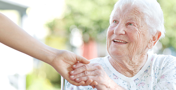 An Elderly Woman Smiling While Holding Hands With Another Person